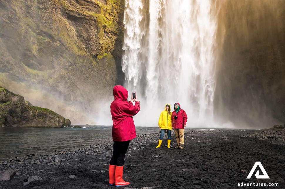 taking picture of two friends near skogafoss waterfall