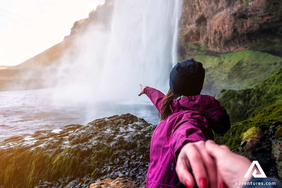 leading a person behind seljalandsfoss waterfall in iceland