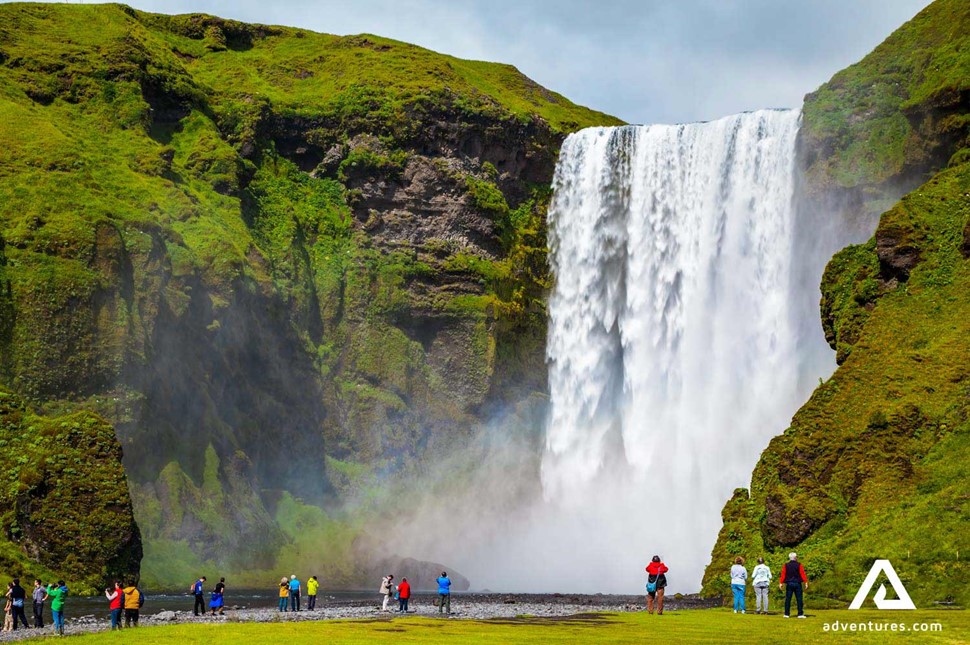 people walking near skogafoss waterfall