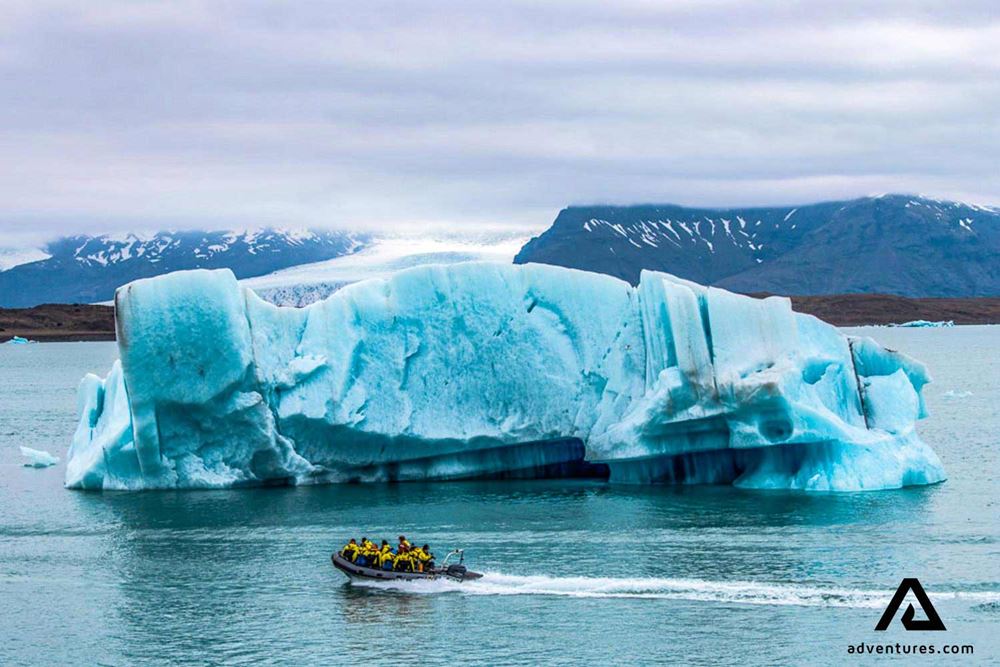 a zodiac boat near a big iceberg