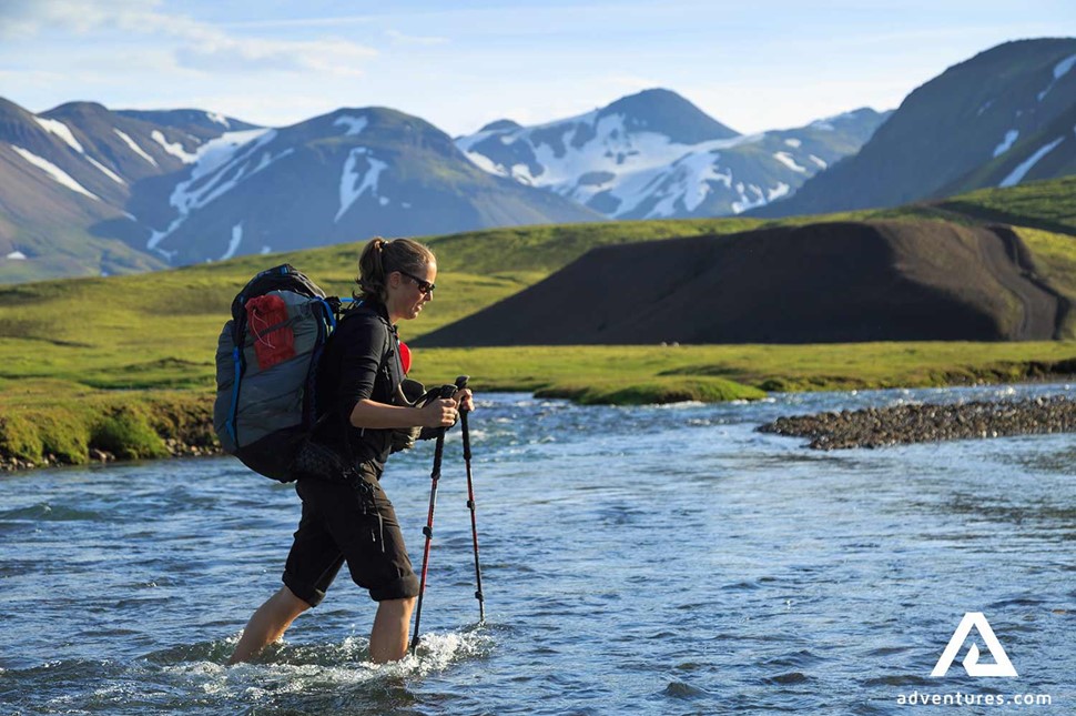 woman crossing a river in iceland on the laugavegur trail