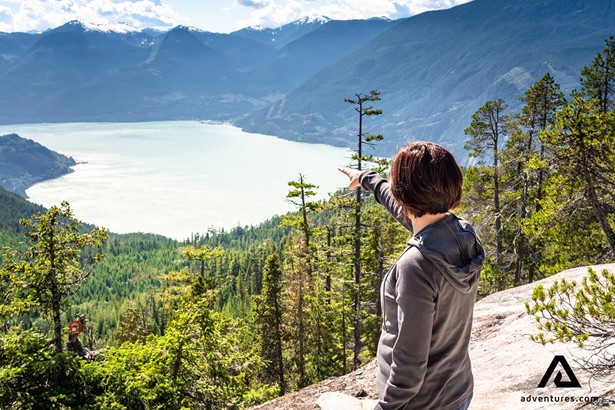 woman pointing at a large lake from a mountain