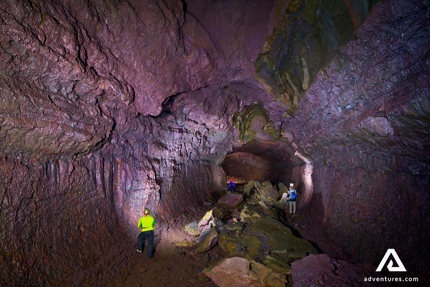 people exploring deep old lava cave 