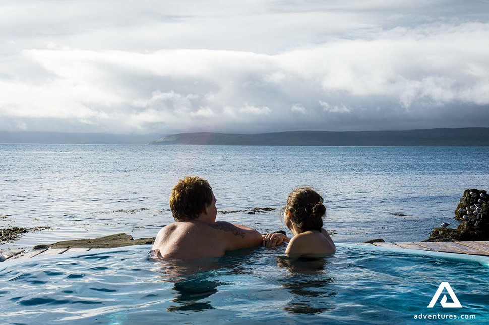 Couple Enjoying Geothermal Pool Ocean Sea Beach Westfjords in Iceland