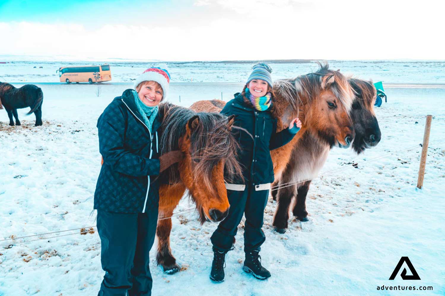 two happy women petting horses