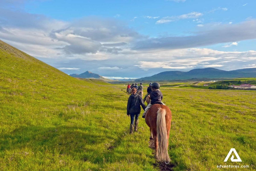 riding horses through a field in the north of Iceland