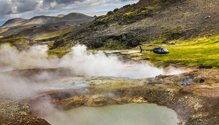 steaming geothermal fields next to a helicopter in hveragerdi