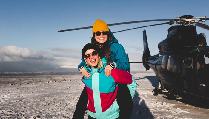 two happy friends on a helicopter tour in winter
