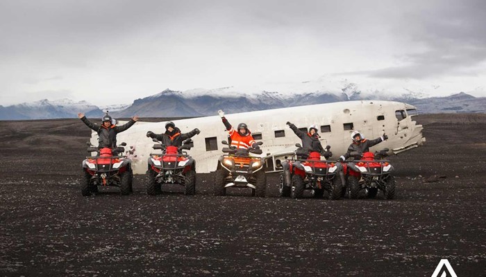 happy group with atvs near a plane wreck in iceland