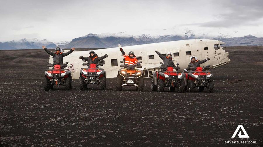 happy group with atvs near a plane wreck