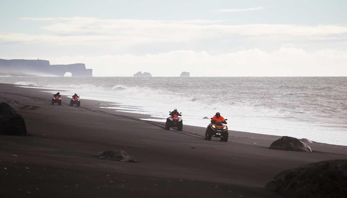 riding atvs on a black sand beach in south iceland