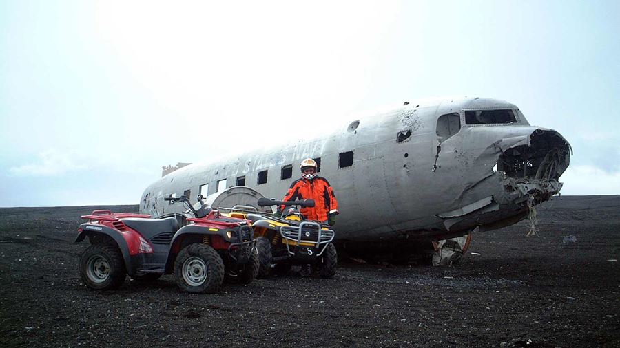 man with an atv next to a plane wreck