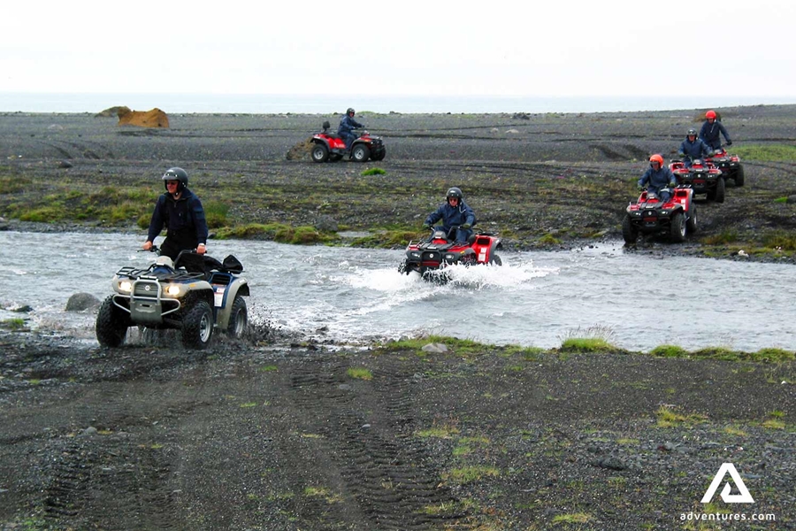 group with quad bikes crossing a river in solheimasandur