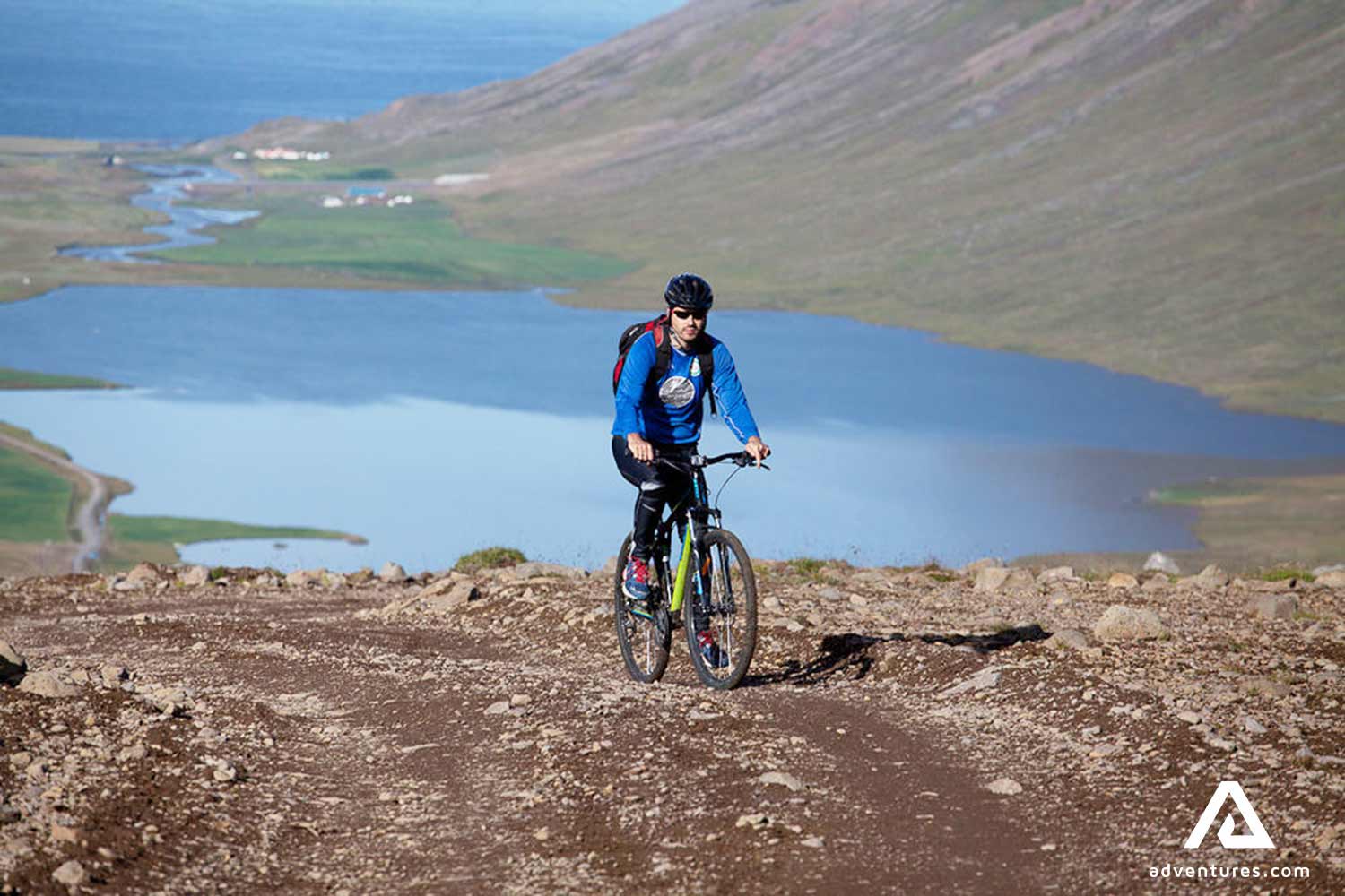 a man riding bike uphill near a fjord