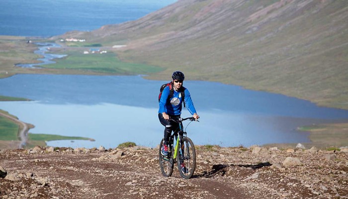 a man riding bike uphill near a fjord