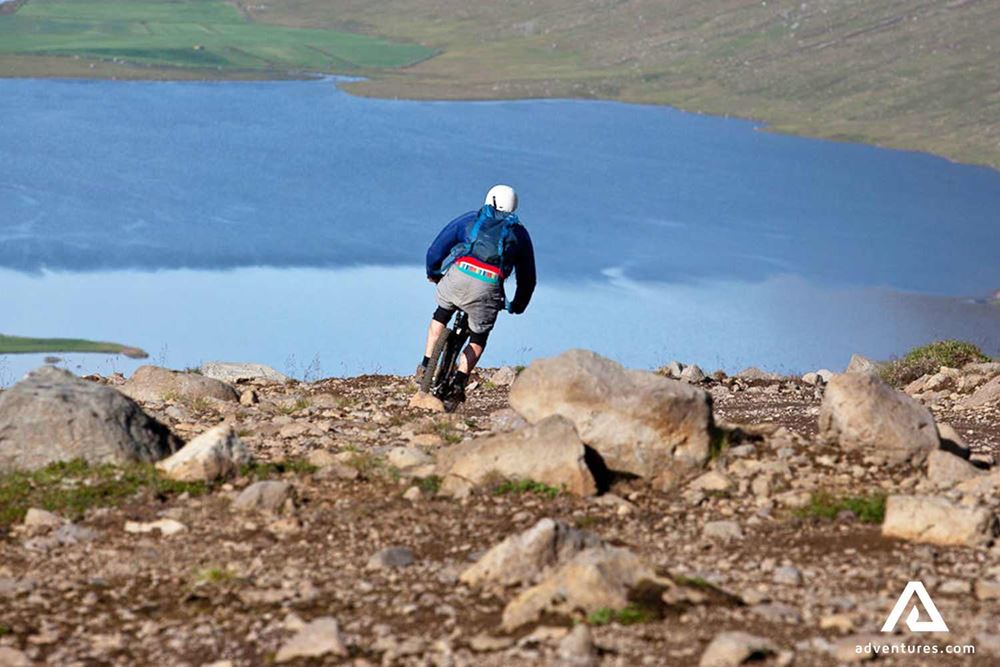 riding a mountain bike down a hill towards a fjord