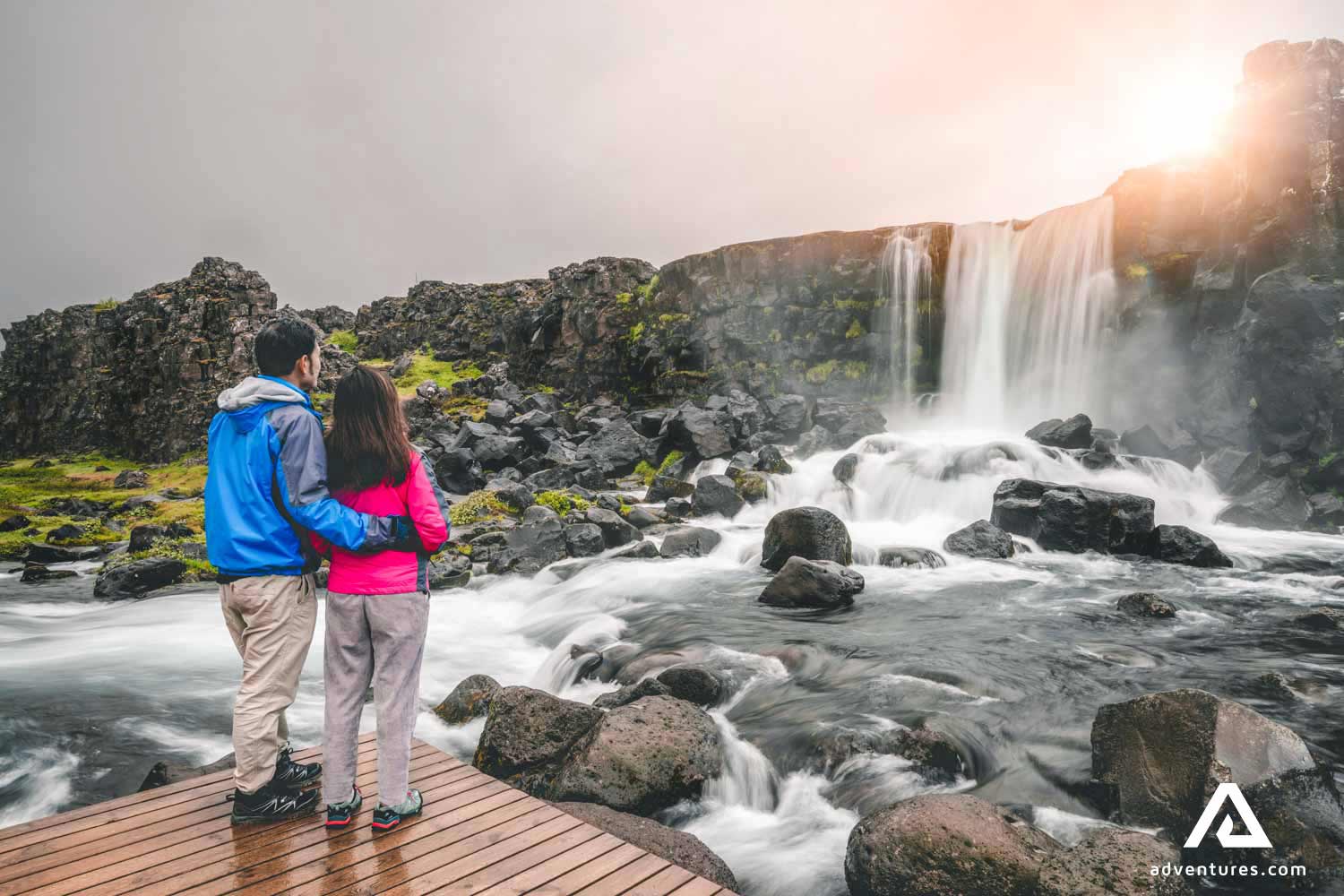 A couple standing near Oxararfoss waterfall