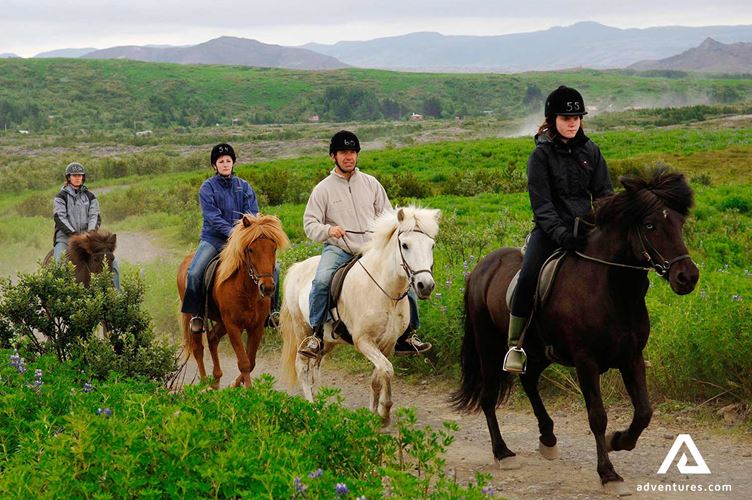 riding with horses through a green field people riding with horses through a green field