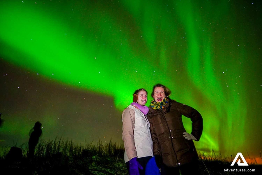 Two happy friends watching northern lights