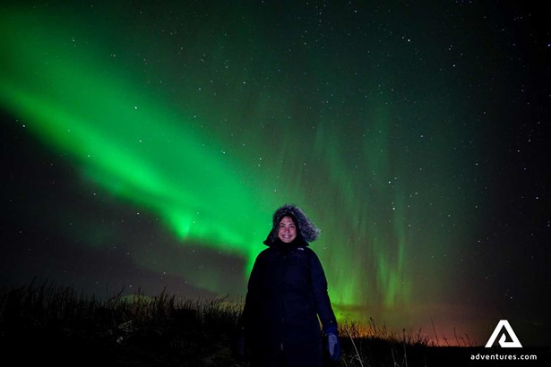 a happy woman watching northern lights on a tour