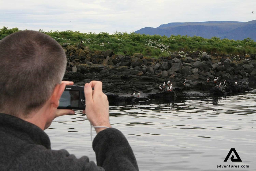 a man taking pictures of puffins
