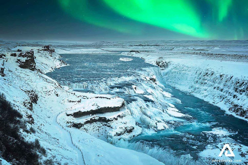 gullfoss waterfall in winter with bright green northern lights