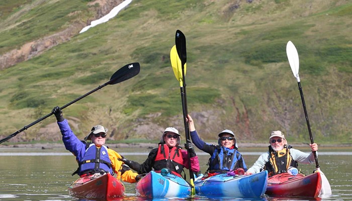 Group raising hands with kayaking paddles