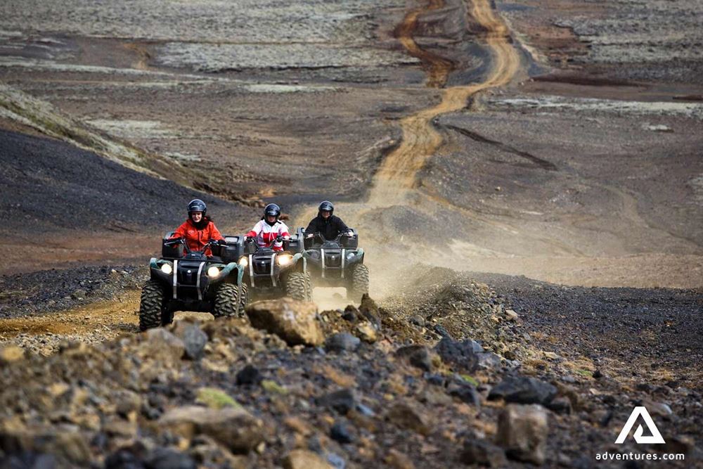 People riding a long gravel road with ATV