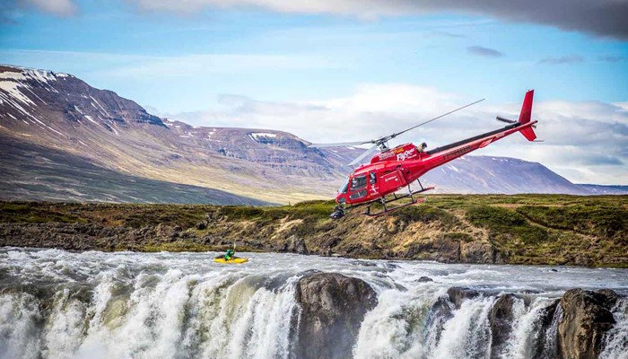 helicopter flying over a waterfall with a camera in iceland