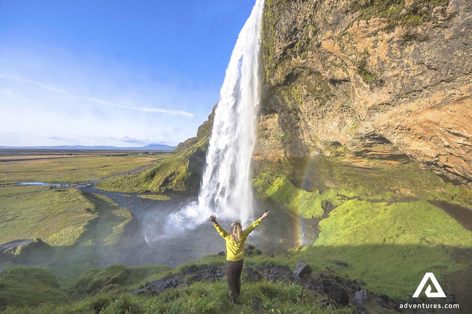 happy woman near seljalandsfoss waterfall in south coast