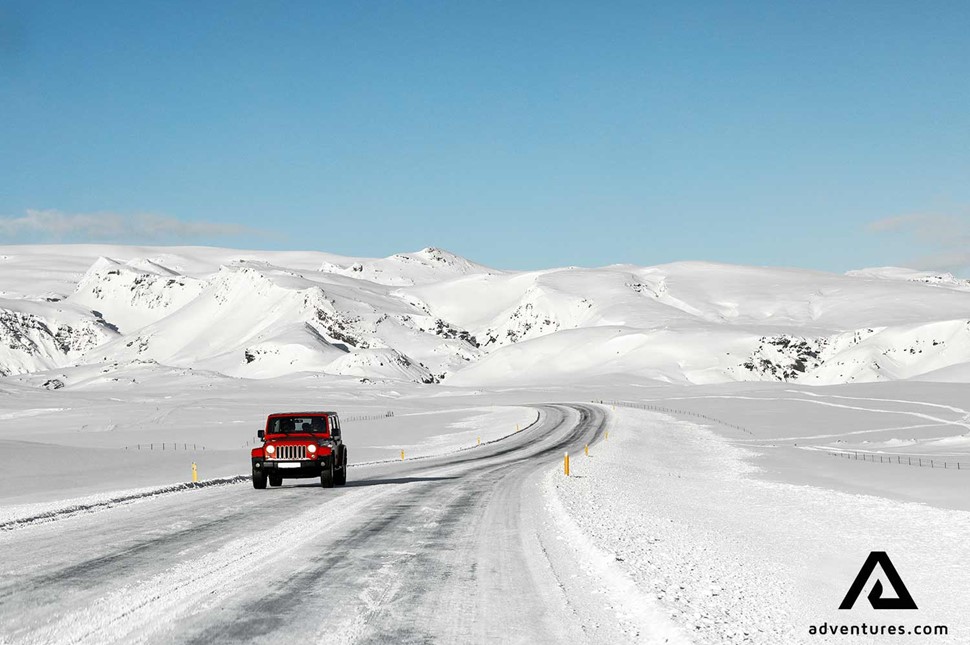 red jeep driving a winter road in iceland