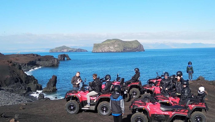 big group riding atvs in vestmannaeyjar near cliffs