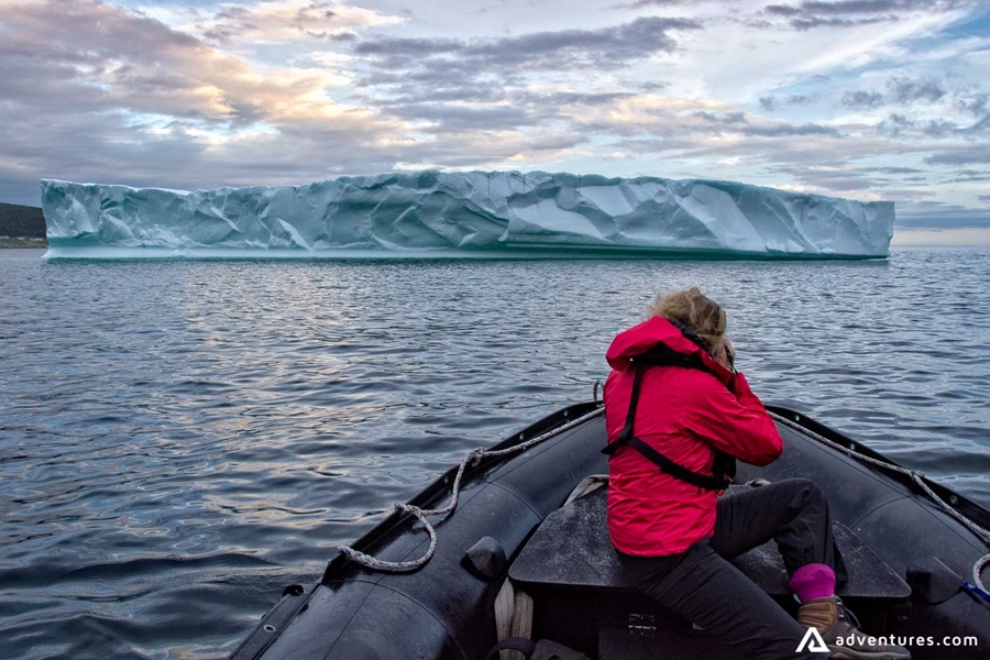 Woman taking pictures of an iceberg from a boat