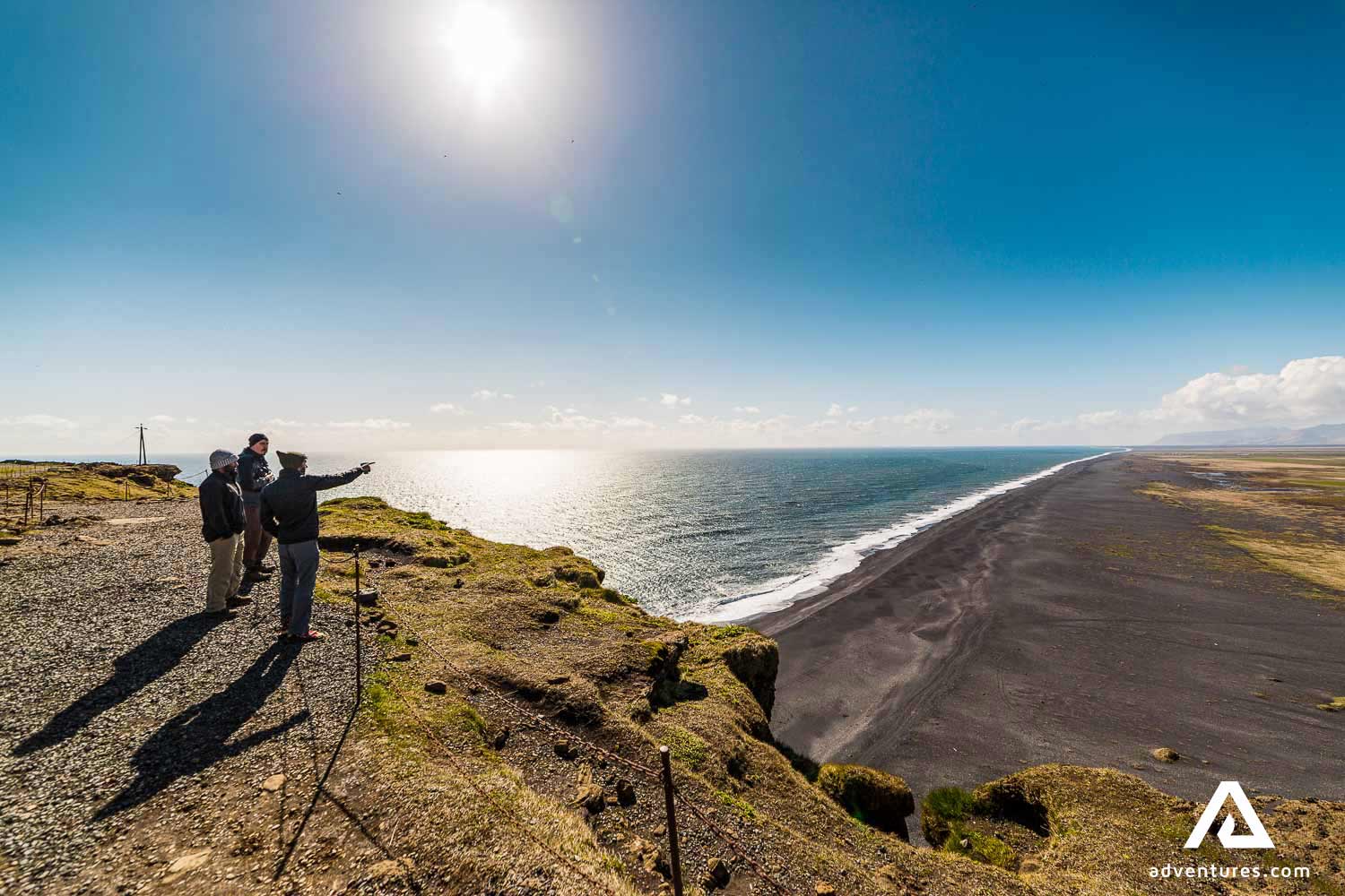 three people watching the beach from dyrholaey