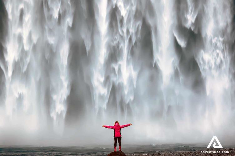 woman near a powerful waterfall woman near a powerful waterfall Skogafoss