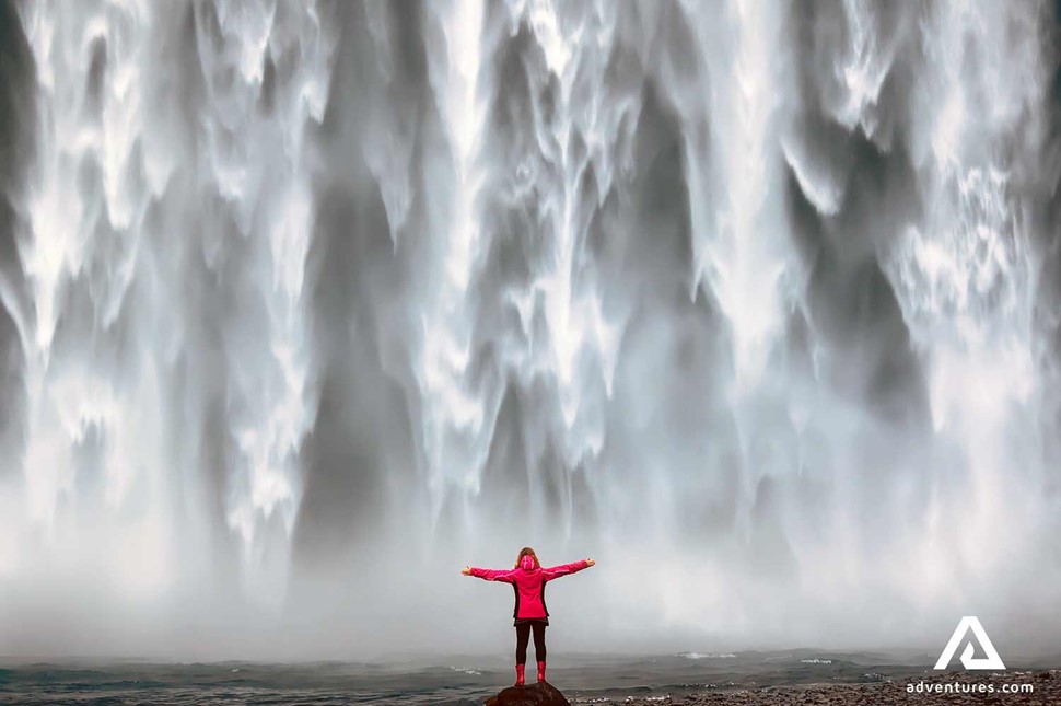 woman near a powerful waterfall Skogafoss