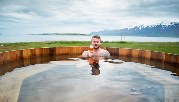 man with beer in a hot tub outside the beer spa near dalvik