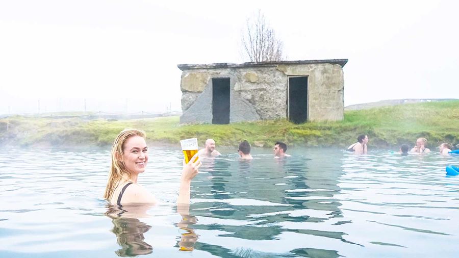 happy woman raising a beer cup in secret lagoon