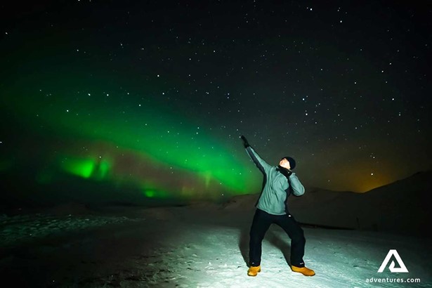 man posing for a picture near northern lights in iceland