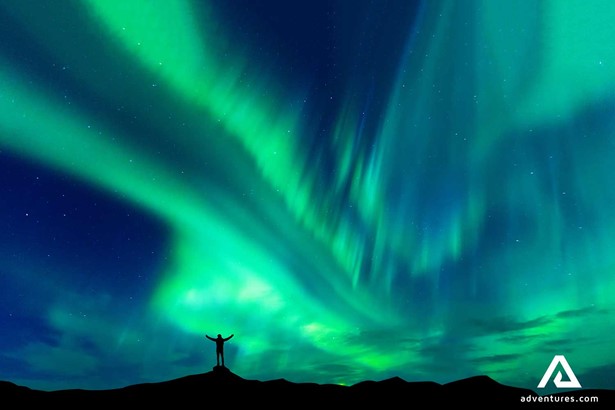 spreading arms in happiness near aurora borealis bright lights