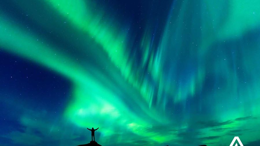 spreading arms in happiness near aurora borealis