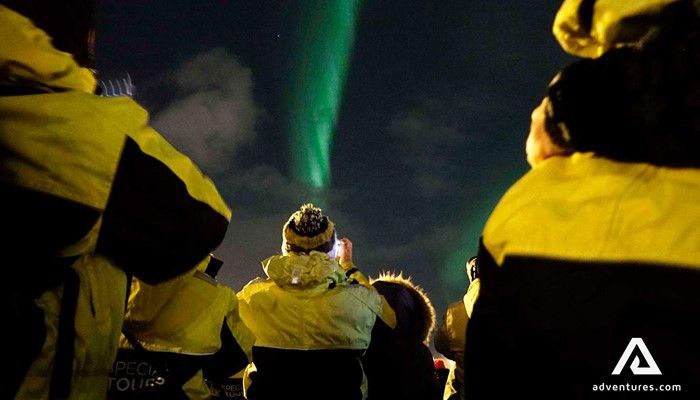 group of people taking pictures of northern lights on a tour
