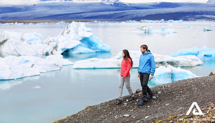 couple walking around jokulsarlon glacier lagoon in south iceland
