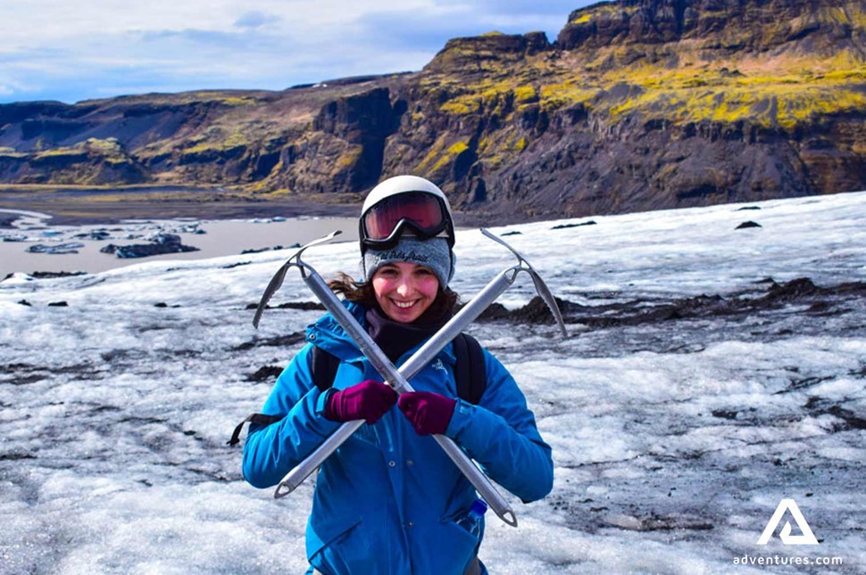 happy woman with ice axes on a glacier in iceland
