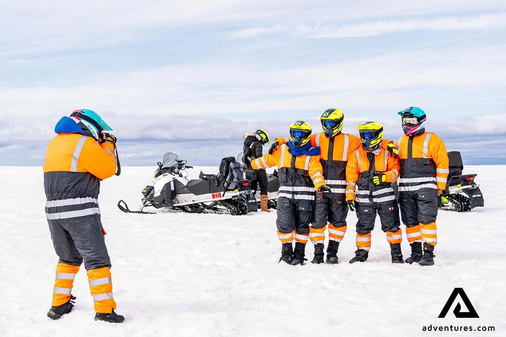 taking group picture near snowmobiles