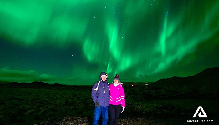posing for a picture near northern lights in iceland