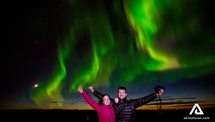 couple with hands open near northern lights in iceland