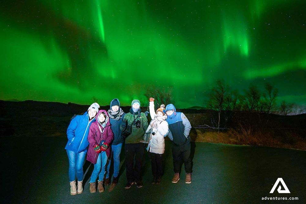 group of friends watching aurora borealis