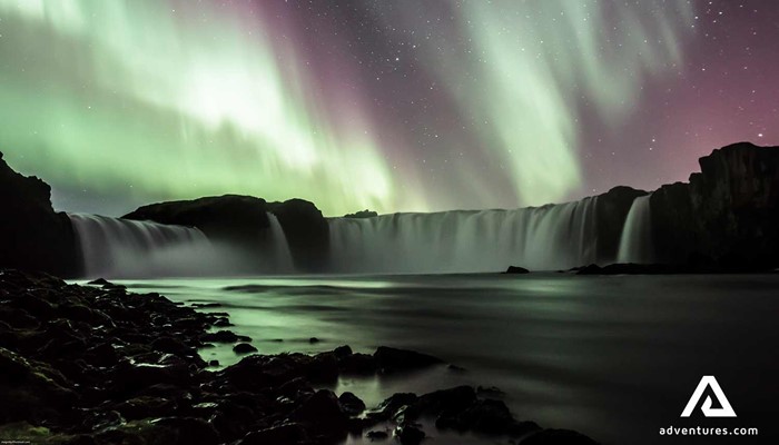 northern lights above godafoss waterfall in winter