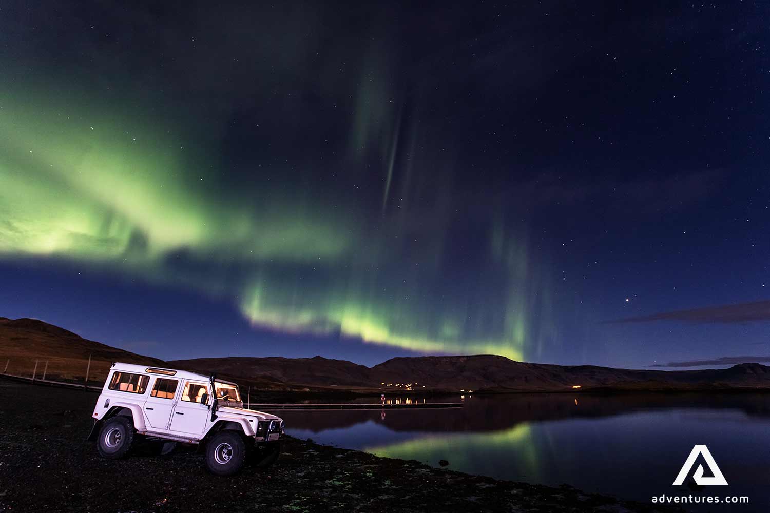 land rover jeep near northern lights in iceland